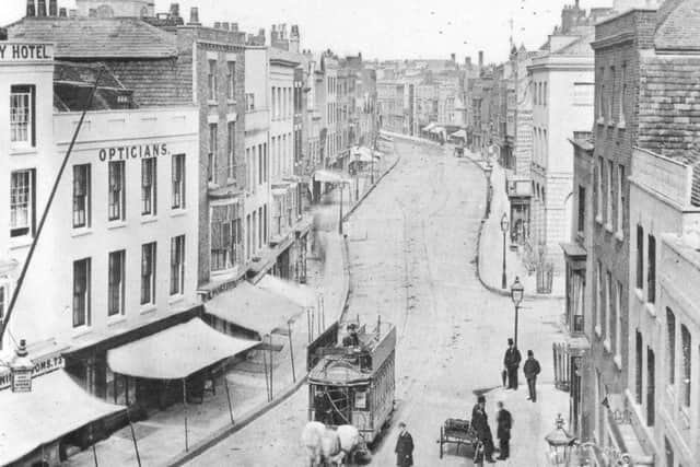 Imposing High Street, Old Portsmouth, with the shops canopies anchored in the kerbs and the cathedral tower top left