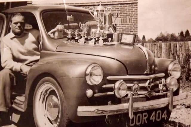 Tom Sprake with his Renault and some of his rallying trophies.