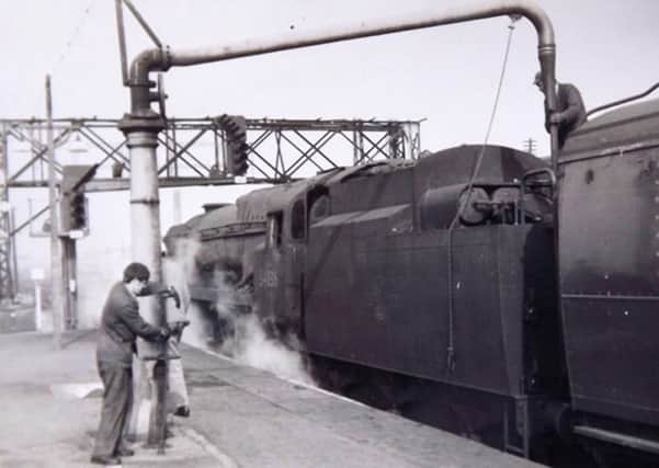A young John Gardner assisting his driver by filling up the loco tender with water at Basingstoke  in 1967