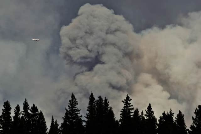 A plane surveys the area near a wildfire in Fort McMurray, Alberta, on Thursday, May 5, 2016. An ever-changing, volatile situation is fraying the nerves of residents and officials alike as a massive wildfire continues to bear down on the Fort McMurray area of northern Alberta. The province of Alberta declared a state of emergency. Picture: Jason Franson/The Canadian Press via AP