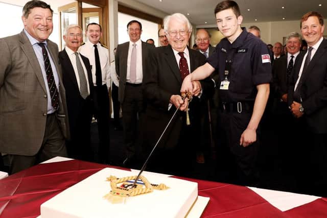 Rear Admiral Lockyer cutting HMS Sultan's 60th anniversary cake with the base's youngest trainee, Engineering Technician Jordan Chaplin