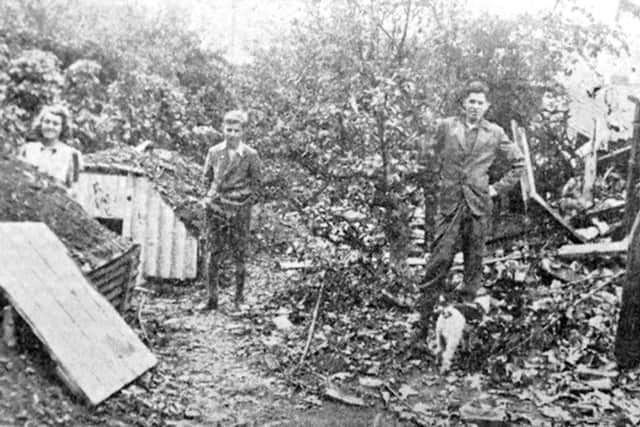 The family by the crater caused by the bomb that just missed their Anderson shelter