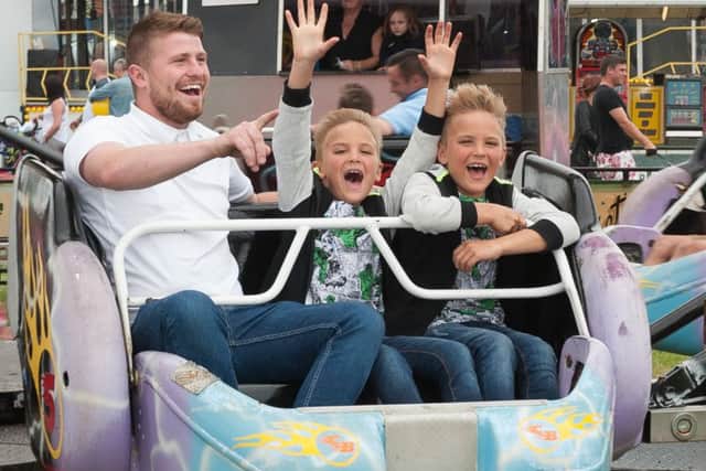 Louis Frampton and twins Reiley and Reggie, six, enjoy one of the funfair rides Picture: Keith Woodland