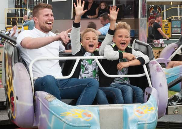 Louis Frampton and twins Reiley and Reggie, six, enjoy one of the funfair rides Picture: Keith Woodland