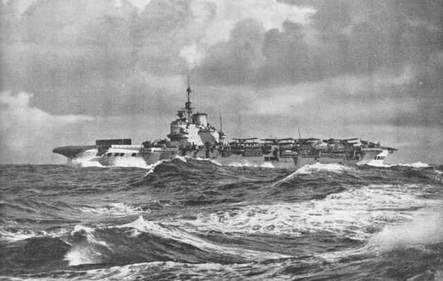 The legendary HMS Victorious under stormy skies in 1943. The black shield forard is a wind barrier to protect the aircraft.