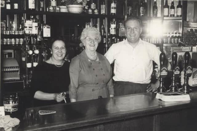 Gladys Hopping (centre) behind the bar with Jack Froggatt and his wife