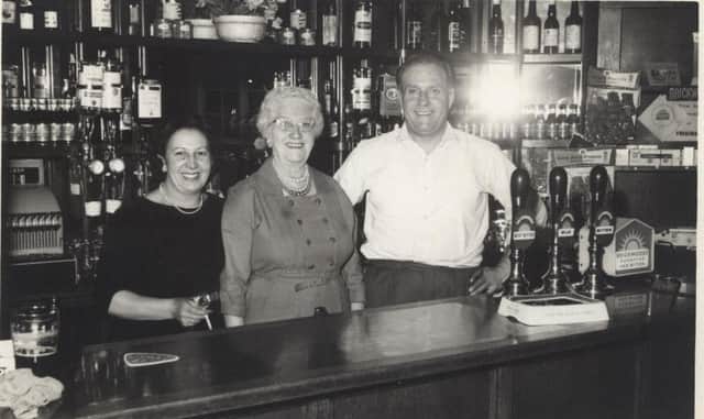 Gladys Hopping (centre) behind the bar with Jack Froggatt and his wife