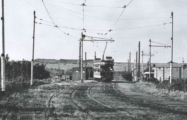 A tram bound for Horndean crosses the bridge over the buses only side road with the bridge over the railway line just ahead of it.