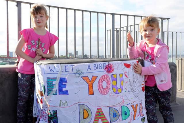 Megan and Erin Bibb showing the banner they made for their Father Warrant Officer 1 A Bibb of HMS Diamond
