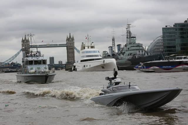 The UKs Maritime Autonomy Surface Testbed, an unmanned surface vessel, undergoing trials in the tidal Thames. Also in shot is the patrol vessel HMS Archer in front of Tower Bridge