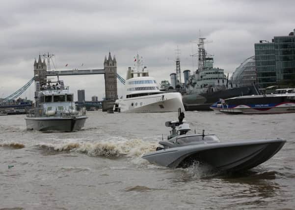 The UKs Maritime Autonomy Surface Testbed, an unmanned surface vessel, undergoing trials in the tidal Thames. Also in shot is the patrol vessel HMS Archer in front of Tower Bridge