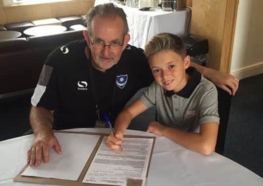 Eleven-year-old Aaron Flahavan signs on the dotted line for Pompey in the company of the Blues head of education and welfare, Jon Slater