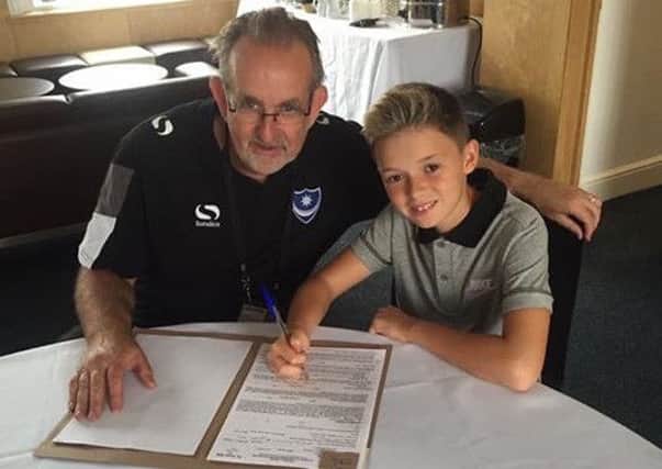 Eleven-year-old Aaron Flahavan signs on the dotted line for Pompey in the company of the Blues head of education and welfare, Jon Slater