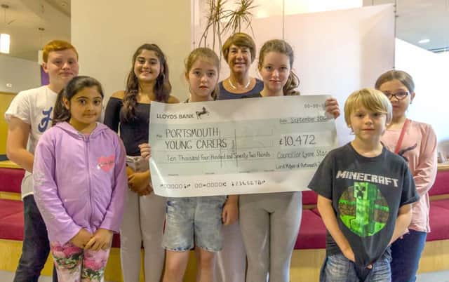 Cllr Stagg presenting the cheque to young carers Oliver, Maryam, Maaria, Hannah, Olivia, Jake, Kirstie