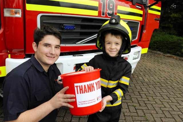 Firefighter Marley Cameron, 22, helps George McKenna, five, with a hi-tech helmet that includes face protection and a video camera for the user and between them they carry a bucket for The Firefighters Charity Picture: Malcolm Wells (160917-5896)