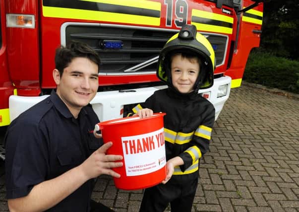 Firefighter Marley Cameron, 22, helps George McKenna, five, with a hi-tech helmet that includes face protection and a video camera for the user and between them they carry a bucket for The Firefighters Charity Picture: Malcolm Wells (160917-5896)