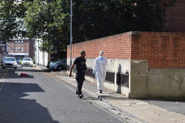 A police officer and an officer in a forensic suit survey the scene in Lansdowne Street, Southsea (October 2, 2016) PPP-160210-115331001