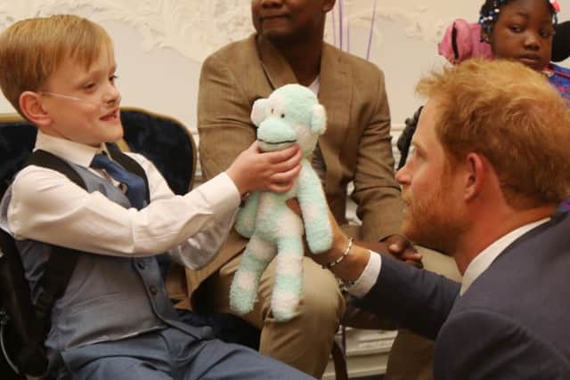 Sam Merrick meets Prince Harry and presents him with Mr Monkey, a homemade teddy made from socks Picture: Antony Thompson - Thousand Word Media