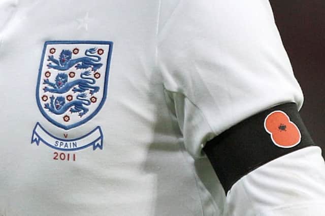 A picture from November 2011 of an England player wearing a black armband with a poppy symbol on aside the England badge.