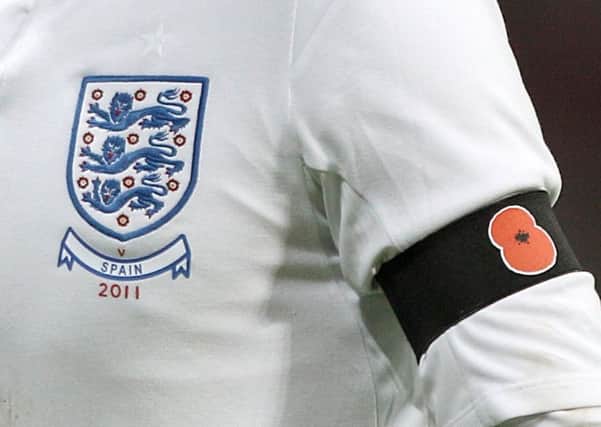 A picture from November 2011 of an England player wearing a black armband with a poppy symbol on aside the England badge.