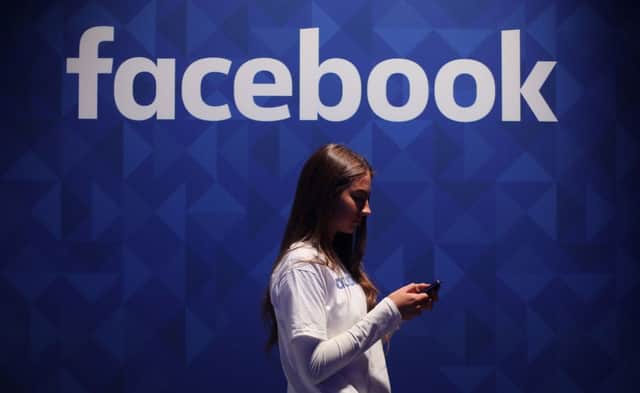 File photo dated 03/11/15 of a woman using her phone under a Facebook logo, as insurer Admiral announced that first-time drivers can receive reduced insurance quotes by allowing their Facebook profiles to be scoured in a bid to determine their personalities. PRESS ASSOCIATION Photo. Issue date: Wednesday November 2, 2016. The insurance company said that those buying their first car could join the optional scheme to receive a discount of up to 15%. See PA story TRANSPORT Facebook. Photo credit should read: Niall Carson/PA Wire TRANSPORT_Facebook_072707.JPG