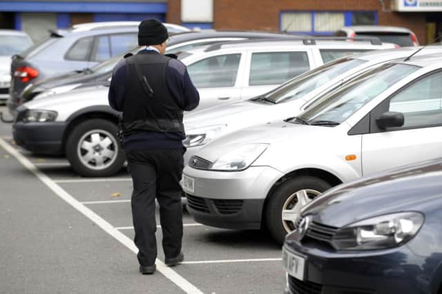 A parking warden checking tickets in Isambard Brunel car park, Portsmouth
