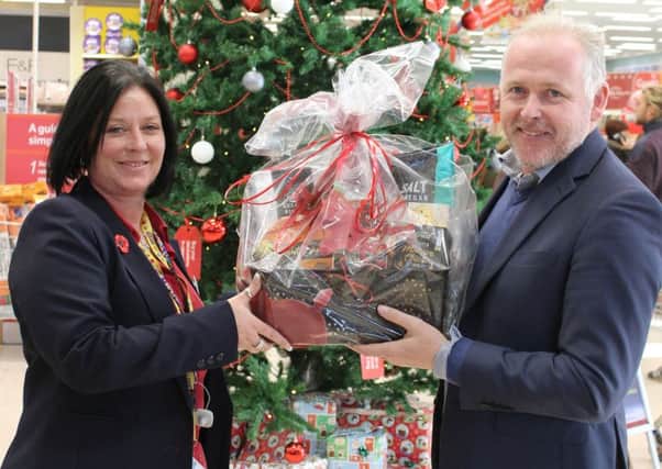 Reverend Mark James holding one of the Christmas hampers with Tesco community champion Mandi Myers