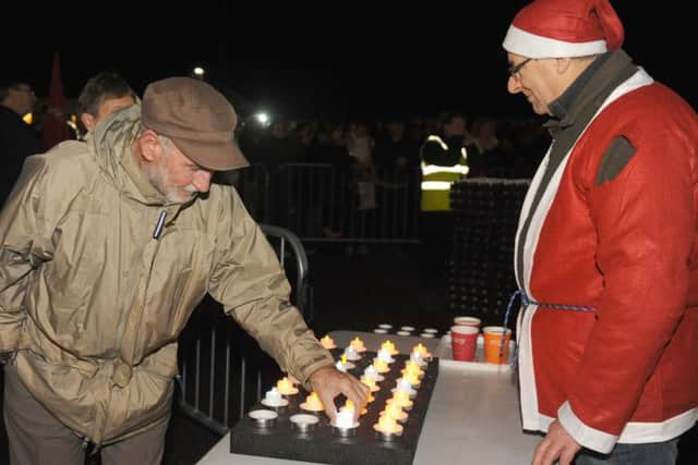 Peter Stafford, 72, from Southsea, left, places his light in one of the trays.

Picture: Sarah Standing (161710-9424)