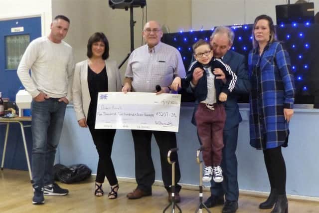 Bill Edwards presenting Aiden Farrell's cheque following the pigeon auction fundraiser with his parent, Gevun and Sara, auctioneer Tony Cowan and his wife Maria