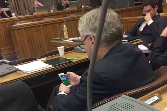 Gerald Vernon-Jackson on his phone playing Solitaire during the latest full council debate in Portsmouth. PPP-161223-122023001