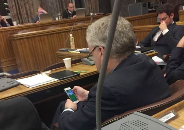 Gerald Vernon-Jackson on his phone playing Solitaire during the latest full council debate in Portsmouth. PPP-161223-122023001