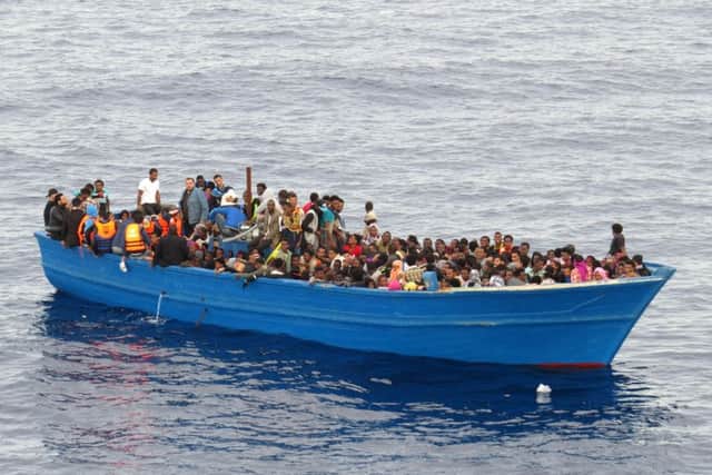 Image shows a large, blue-hulled wooden boat containing 439 migrants prior to rescue by  HMS Enterprise in the Mediterranean sea. PHOTO: Royal Navy