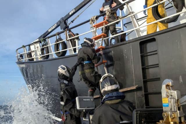 Navy sailors clamber aboard to inspect the fishing vessel