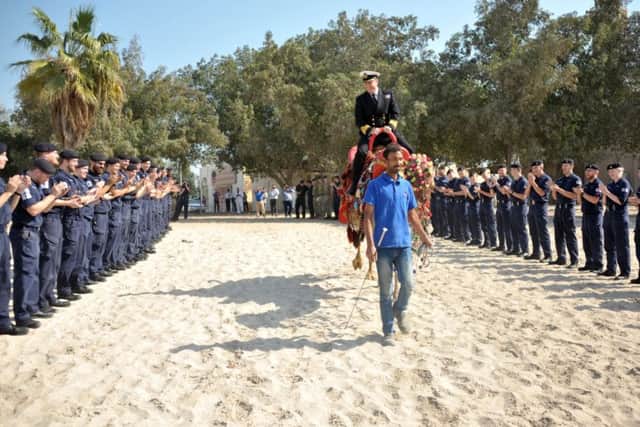 Commander Philip Dennis rides the camel as the ship's company form a 'gauntlet of honour'