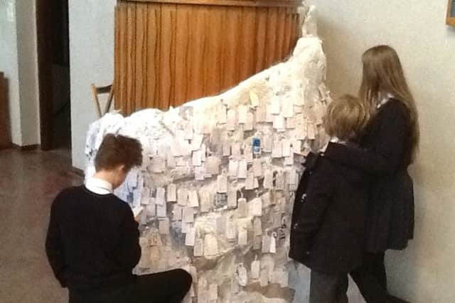 Children add their prayers for others to the sculpture