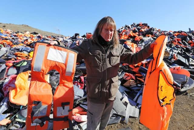 Eric Kempson holds a life jacket next to a fake life jacket (right) as he stands between piles of used life jackets, which he said the majority of  which are fake
Picture: Owen Humphreys/PA Wire