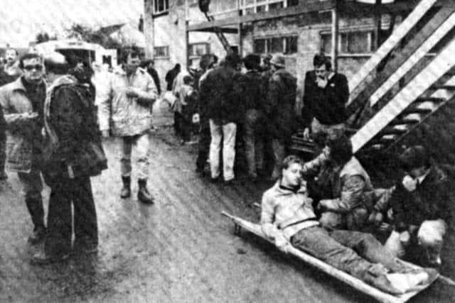 An injured supporter is comforted by while waiting for an ambulance.