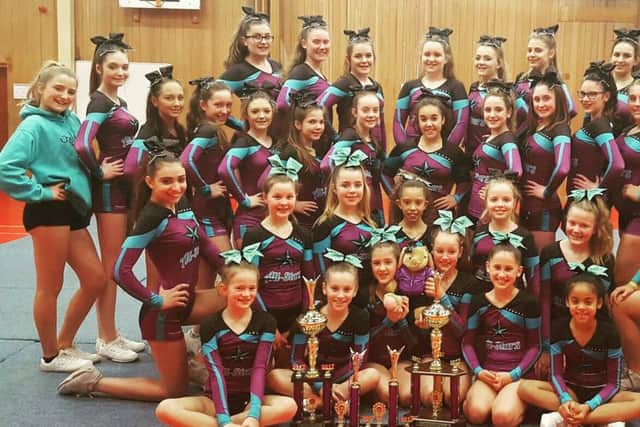 The Cheer-a-cality team are all smiles as they pose with their many trophies