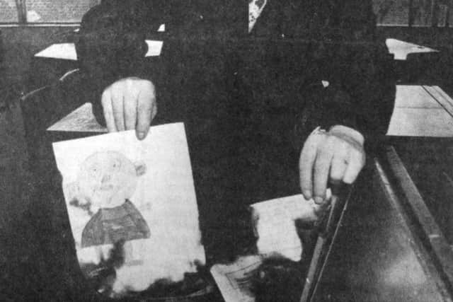 Caretaker Reg Perrit, 60, holds up a piece of burnt paper, one of many found among students' desks at the school (B1293-1)