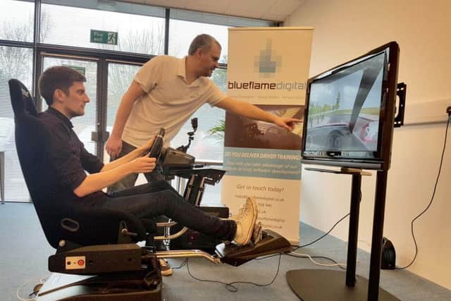 Mark Harman tries out the driving simulator with Dan Hatch, the director of Blueflame Digital