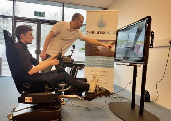 Mark Harman tries out the driving simulator with Dan Hatch, the director of Blueflame Digital