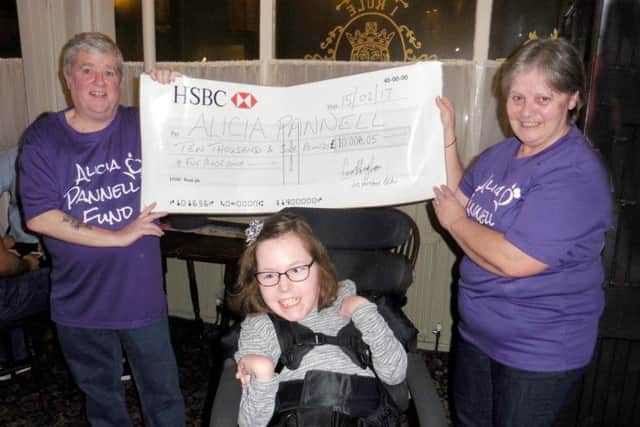 Les Heyhoe BCAv, left, presents Alicia Pannell with a cheque for Â£10,006.05, which will be used to fund a specially designed wheelchair and hoists around the house.CAPTION: Alicia Pannell, centre, is presented with a cheque for Â£10,006.05.