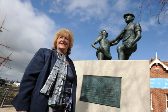 Margaret Foster next to a memorial statue to Mudlarkers at The Hard, Portsmouth