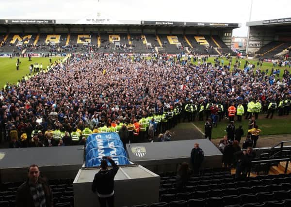 Pompey fans celebrate on the pitch at Meadow Lane after beating Notts County to seal promotion Picture: Joe Pepler