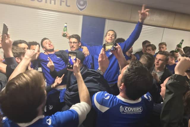 Pompey players, centre, from left, Enda Stevens, Gareth Evans and Christian Burgess, get into the party spirit at Fratton Park following the 3-1 victory at Notts County on Monday that clinched promotion to League One