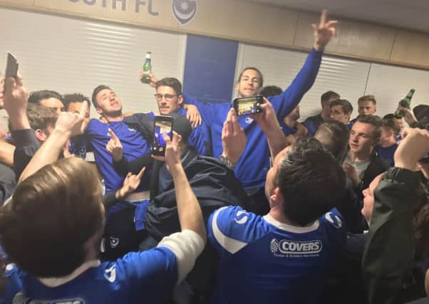 Pompey players, centre, from left, Enda Stevens, Gareth Evans and Christian Burgess, get into the party spirit at Fratton Park following the 3-1 victory at Notts County on Monday that clinched promotion to League One
