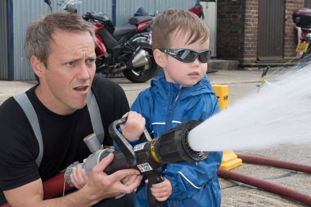 Cosham Fire Station held a car wash in aid of the Fire Fighters Charity and Phil Lamb is assisted by Ben Chamberlain, three, hosing down the vehicles Picture: Keith Woodland (170423-162127001)