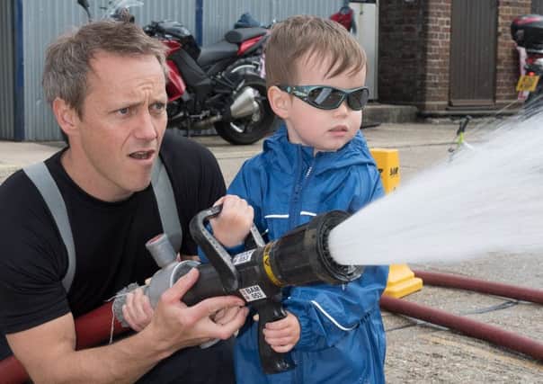 Cosham Fire Station held a car wash in aid of the Fire Fighters Charity and Phil Lamb is assisted by Ben Chamberlain, three, hosing down the vehicles Picture: Keith Woodland (170423-162127001)