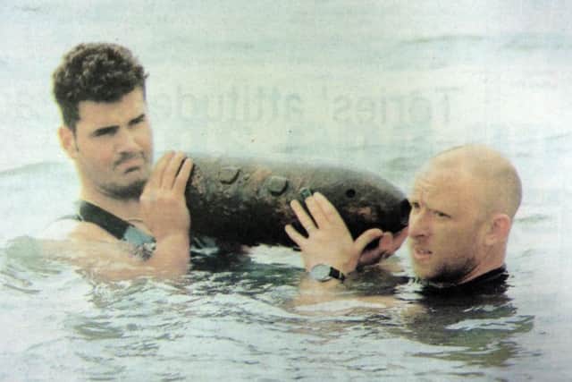 Divers Garry Nicholas-Hovarth-Toldi and Neil Smith lift a defused bomb out of the Solent