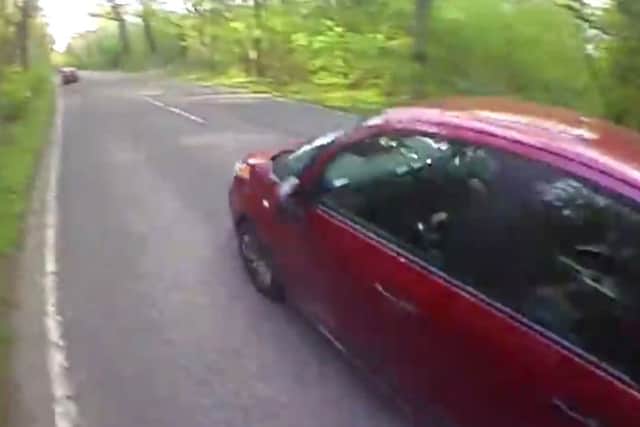 A still from head-cam footage of a car overtaking a cyclist too close